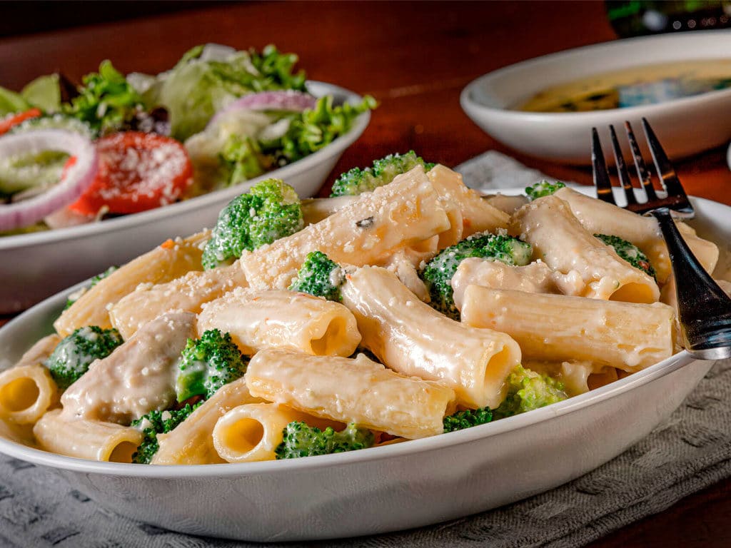 Pasta Rigatoni with Chicken & Broccoli with insalata salad and dipping oil in the background