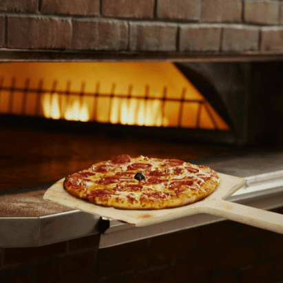 A Bertucci's pepperoni pizza being taken out of a brick oven