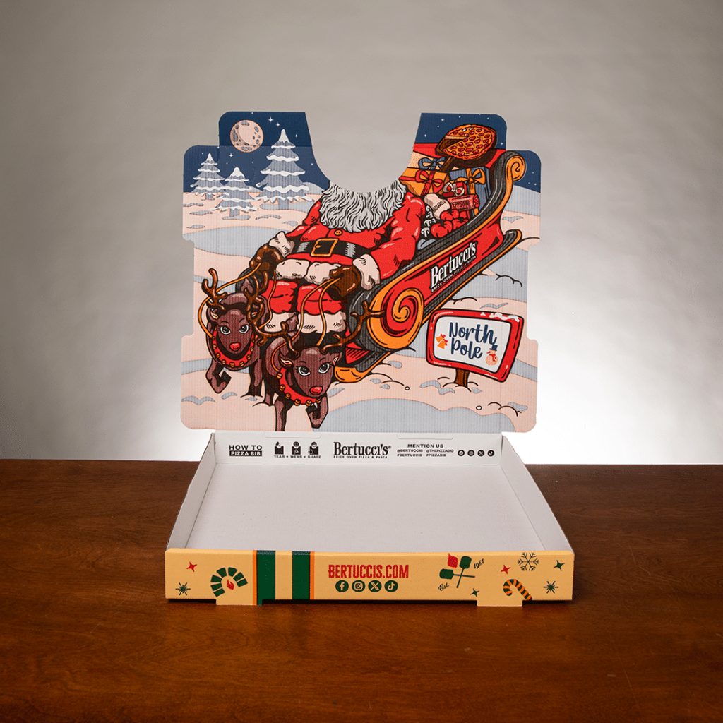 A pizza box with an illustration of santa's sleigh on the inside of the lid