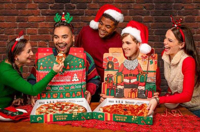 A group of friends posing with the holiday-printed pizza boxes