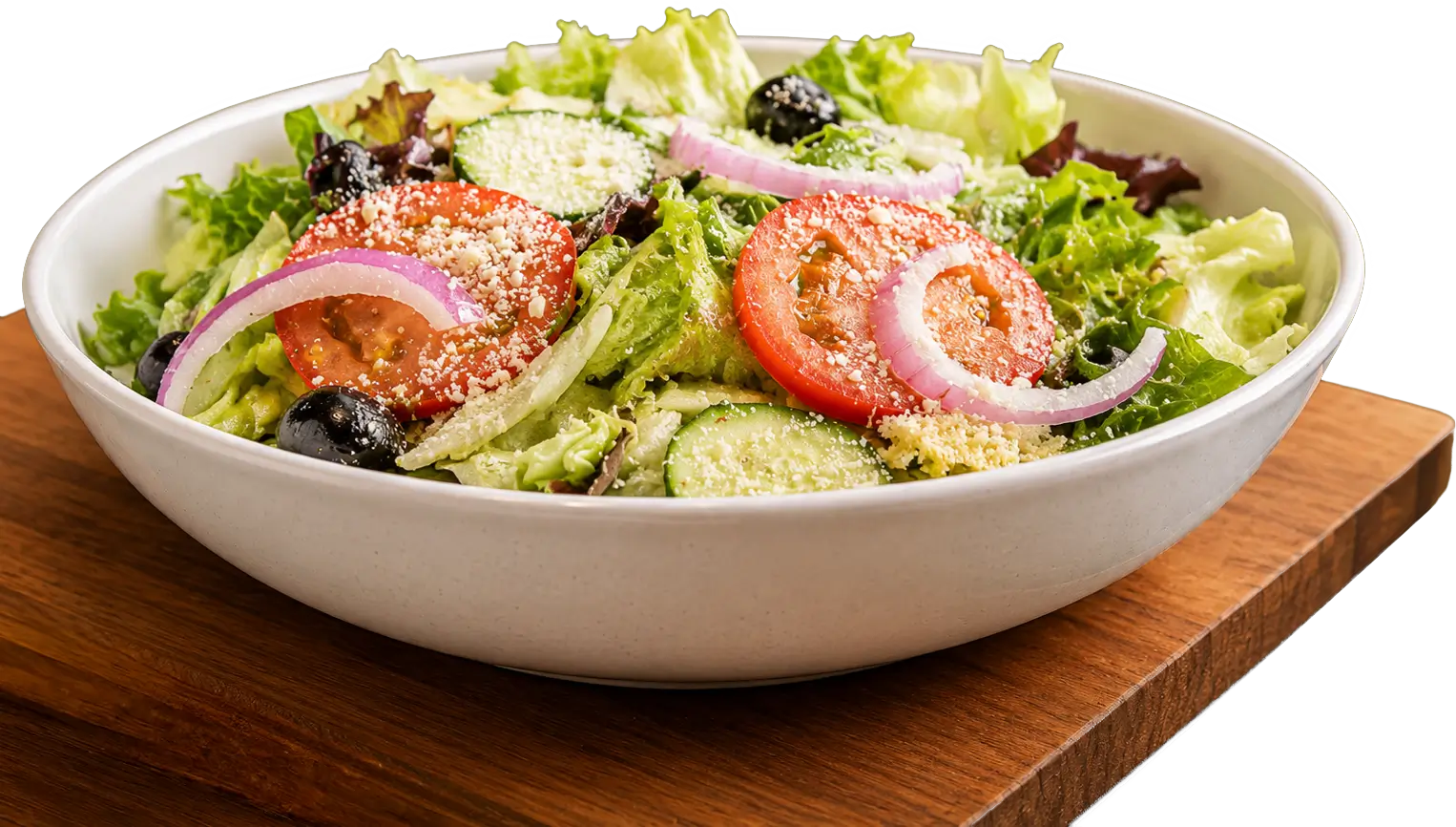 Fresh salad with tomatoes, cucumbers, red onions, black olives, and grated cheese in a white bowl on a wooden board.